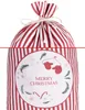 A close-up of a red and white striped Christmas gift bag with a circular design featuring mittens, candy canes, and pine sprigs. Podgląd zdjęcia produktu
