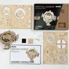 A flat lay of a ROKR Perpetual Calendar 3D wooden puzzle kit, including unassembled wooden pieces, a partially assembled model, packaging, and assembly instructions. Anteprima dell’immagine prodotto