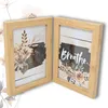 Two wooden photo frames are displayed side-by-side against a white background, with subtle floral graphics in the background. Produktbild-Vorschau