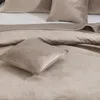 A close-up view of a beige quilted bedspread and pillows. Podgląd zdjęcia produktu
