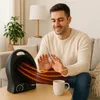 A man is warming his hands in front of a black electric heater in a living room. Produktbild-Vorschau
