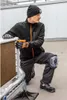 A man wearing work clothes and knee pads is kneeling on a rooftop. Podgląd zdjęcia produktu