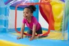 A young girl is playing inside an inflatable trampoline with a slide. Voir les images du produit