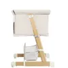 A side view of a baby crib/bassinet with wooden legs and beige fabric. Produktbild-Vorschau