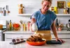 A woman is in a kitchen, preparing a roasted chicken. Náhled obrázku produktu