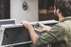 A man is adjusting a blue component on a gray table tennis table. Produktbild-Vorschau