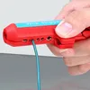 A hand is holding a red wire stripper with a blue label and numbers indicating wire sizes. A teal wire is inserted into one of the stripper's openings. Voir les images du produit