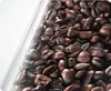 A close-up view of roasted coffee beans, partially obscured by a clear plastic material. Voir les images du produit