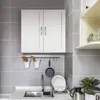 A white cabinet with two doors is mounted on a gray tiled wall above a kitchen sink. Produktbild-Vorschau
