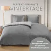 A bed with gray bedding is shown in a room with a floor lamp. Produktbild-Vorschau