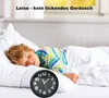A young boy is sleeping peacefully in bed, with an analog alarm clock placed next to him. The scene suggests a quiet and undisturbed environment. Produktbild-Vorschau