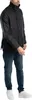 A man wearing a black jacket and blue jeans, standing against a white background. Produktbild-Vorschau