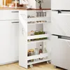 A white kitchen cart with four shelves filled with jars and bottles, placed between a white cabinet and a refrigerator. Podgląd zdjęcia produktu
