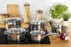 A set of stainless steel pots and pans with glass lids arranged on a stovetop and countertop. Anteprima dell’immagine prodotto