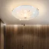 A ceiling light fixture with a white frosted glass shade and a decorative metal design, mounted on a white ceiling above a wall with vertical wooden slats. Podgląd zdjęcia produktu