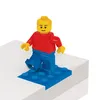 A Lego minifigure standing on a blue Lego base plate, which is placed on a white surface. Produktbild-Vorschau