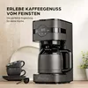 A dark gray drip coffee maker is displayed on a countertop, with two dark gray coffee cups stacked nearby. Text overlays advertise 'ERLEBE KAFFEEGENUSS VOM FEINSTEN' and 'Die perfekte Ergänzung für deine Küche'. Produktbild-Vorschau