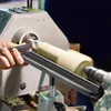 A person is using a wood lathe to shape a piece of wood. A tool rest is positioned to support the woodturning tool. Náhled obrázku produktu