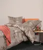 A neatly made bed with a floral pattern duvet cover and a coral throw blanket. Produktbild-Vorschau