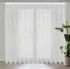 A white sheer curtain is hung in front of a window. Podgląd zdjęcia produktu