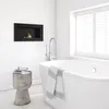 A modern bathroom with a freestanding bathtub, a wall-mounted bioethanol fireplace, and a small stool. Náhled obrázku produktu