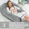 A woman is lying on a large U-shaped pillow in a bedroom setting. Produktbild-Vorschau