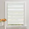 A white roller blind with horizontal stripes of opaque and sheer fabric is installed in a white window frame. A vase with orange flowers is placed on a shelf to the left of the window. Produktbild-Vorschau