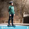 A young boy wearing protective gear rides a hoverboard outdoors. Produktbild-Vorschau