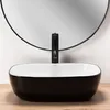 A black and white vessel sink with a black faucet is shown in a bathroom setting. Náhled obrázku produktu