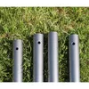 Four metal poles are laid out on a grassy surface. Produktbild-Vorschau