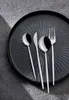 A set of cutlery on a textured black plate. Náhľad obrázku produktu