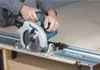 A person is using a Makita circular saw on a track guide to cut a piece of wood. Produktbild-Vorschau