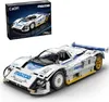 A detailed model of a white and blue Mazda 787B race car, with a box of the same model in the background. Produktbild-Vorschau