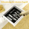 A hand reaching into a kitchen drawer to pick up cutlery from a black organizer. Produktbild-Vorschau