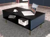 A modern living room scene featuring a black coffee table with blue ribbed accents and gold legs, a laptop, a cup of coffee, and books. Náhled obrázku produktu