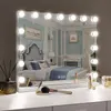 A vanity mirror with lights on a dresser, reflecting a bedroom scene. Produktbild-Vorschau