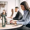 People in an office setting, with a water bottle in the foreground. Voir les images du produit