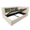 A beige upholstered bed frame with its mattress support mechanism open, revealing storage space underneath. The headboard features integrated shelving and a drawer. Produktbild-Vorschau
