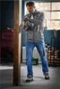 A man is using a cordless drill to work on a wooden beam in a workshop. Produktbild-Vorschau