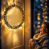 A young girl holding a mug looks up at a lit wreath. Anteprima dell’immagine prodotto