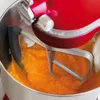 A close-up shot of a red KitchenAid stand mixer's bowl and beater, with an orange mixture being blended. Voir les images du produit