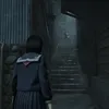 A young girl in a school uniform stands in a dark, narrow alleyway, looking up a set of stairs where shadowy figures are visible. Náhled obrázku produktu