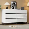 A white sideboard with six drawers and black accents is shown in a room with a wooden wall and a grey carpet. Decorative items are placed on top of the sideboard. Produktbild-Vorschau