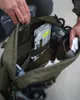 A person is shown reaching into an open green bag, revealing various medical supplies inside. Produktbild-Vorschau