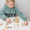 A young boy is playing with dominoes on a white table. Produktbild-Vorschau
