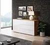 A modern white and wood dresser in a room with a brick-like dark gray wall and a large window overlooking a forest landscape. Náhled obrázku produktu