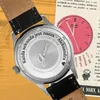 Close-up of the back of a watch with engraved text and a pink clock graphic in the background. Produktbild-Vorschau