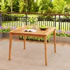 A wooden table on a deck with plants and a railing in the background. Anteprima dell’immagine prodotto