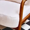 A close-up view of a cream-colored armchair with a wooden frame, set against a black and white checkered floor. Produktbild-Vorschau