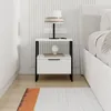 A modern white nightstand with a drawer and shelf, placed next to a bed. Produktbild-Vorschau